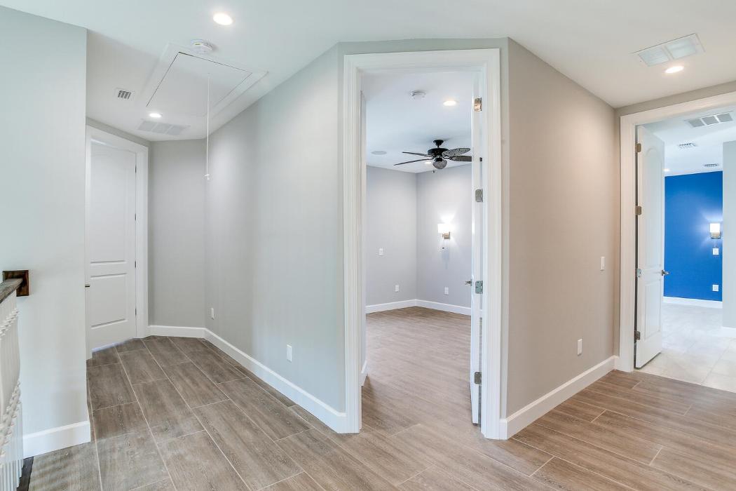 Modern bedroom or sitting area with wood-look flooring, recessed lighting, built-in shelving niche, and a large window with water views.