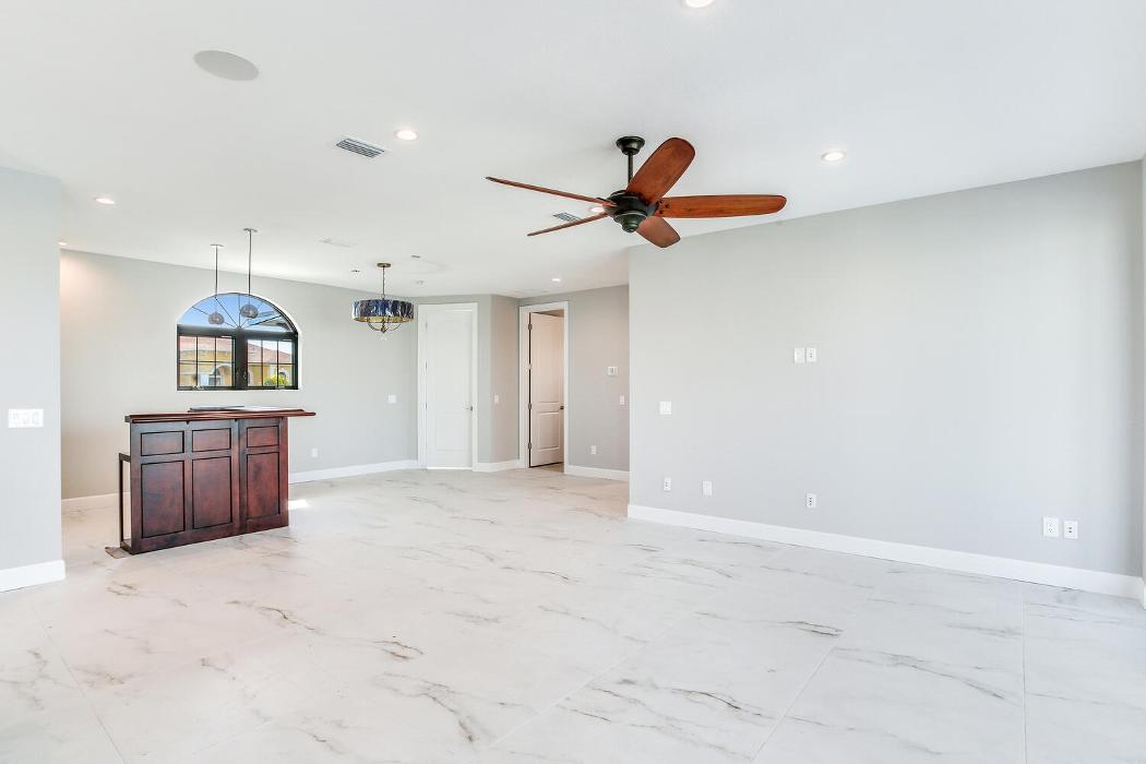 Spacious open interior room with light tile flooring, white walls, recessed lighting, and a ceiling fan.