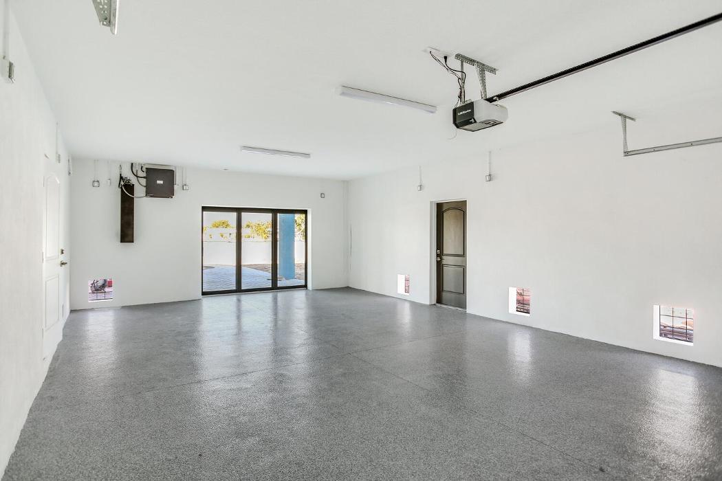 Large unfinished garage or flex space with gray flooring, white walls, ceiling fans, and an open layout leading to exterior doors.