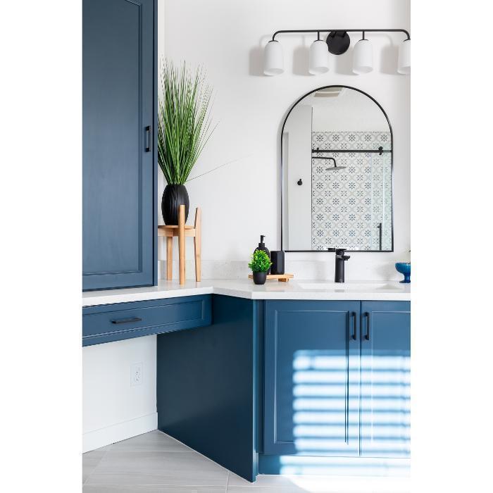 Bold Navy Blue Vanity with Arched Mirror
A striking, design-forward bathroom anchored by deep navy/slate blue shaker-style cabinetry with matte black bar pulls throughout.
