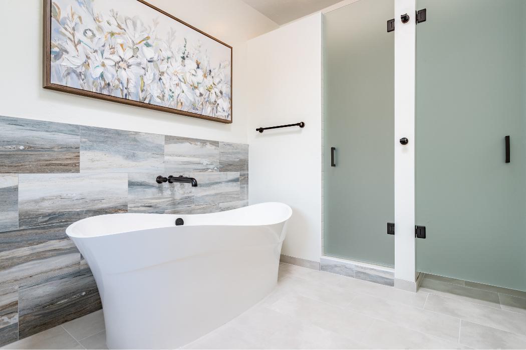 A serene, gallery-worthy bathroom with a sophisticated, understated palette. The star of the space is a sculptural modern freestanding soaking tub in glossy white with a dramatic high-back slipper silhouette — sleek and architectural in form.