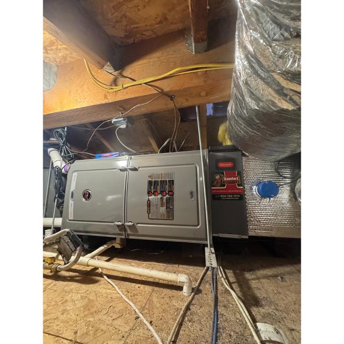 A piece of restoration or drying equipment set up in a crawlspace or basement area with exposed insulation and ductwork overhead.