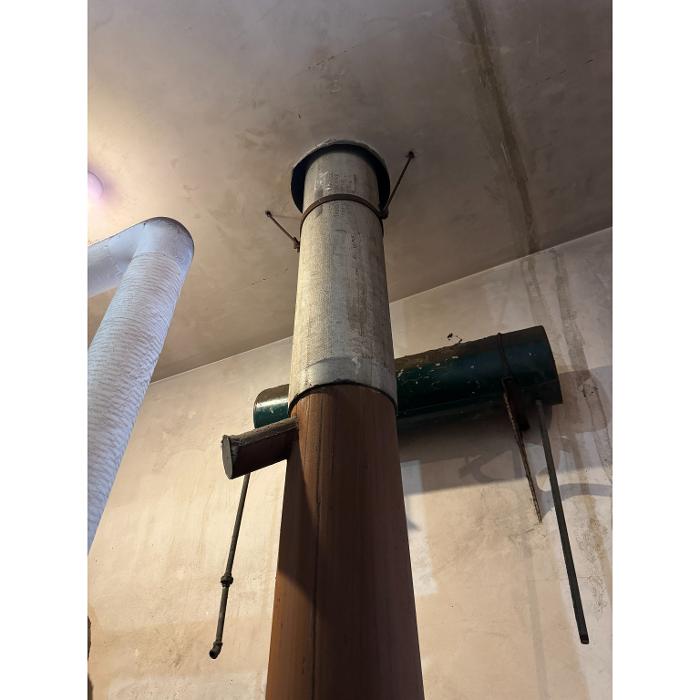 A vertical pipe or support column inside a basement or utility area, with attached inspection or monitoring equipment near the top.