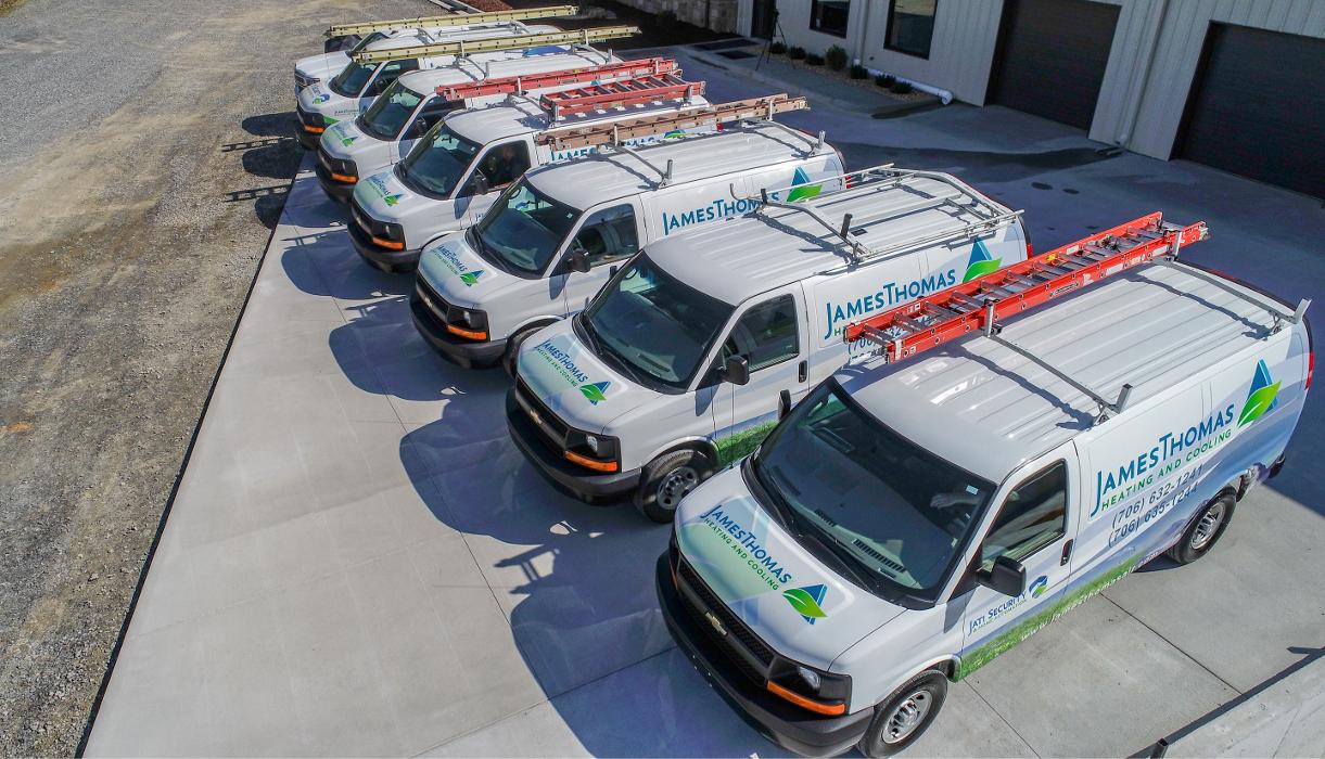 Aerial view of multiple branded service vans parked in a row beside the business location.