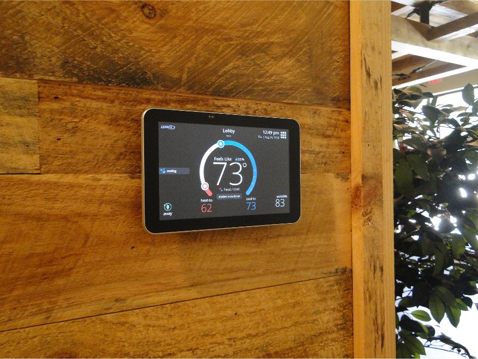 Smart thermostat mounted on a wood wall, highlighting modern temperature control technology for home comfort.