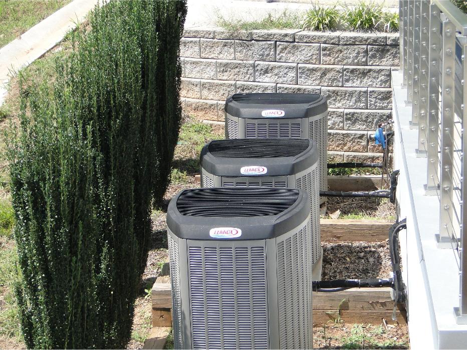 Row of outdoor HVAC units installed along the side of a property, showcasing multiple residential cooling systems.