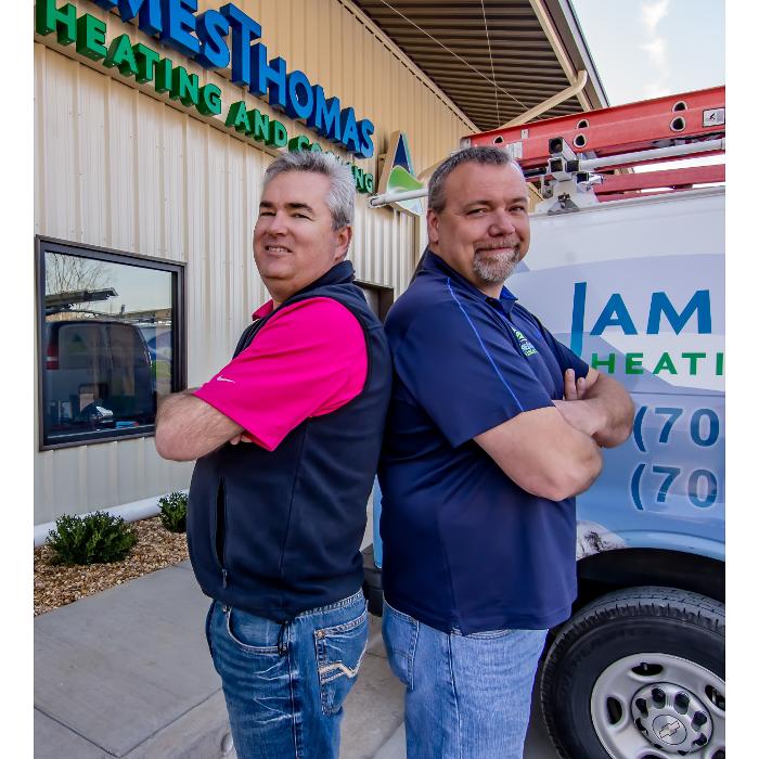 Two smiling team members standing outside the business location next to a branded service van.