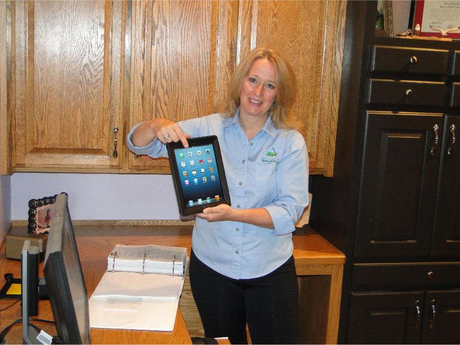 Happy customer standing in her kitchen holding a tablet, highlighting a positive home service experience.