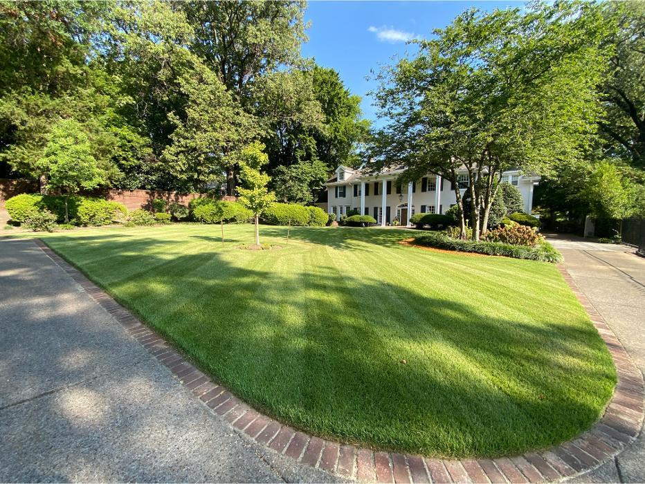 Freshly maintained striped front lawn and trimmed landscape surrounding a large residential property.