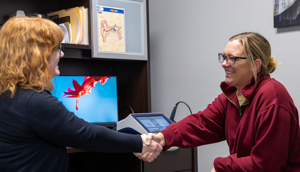 person shaking hands with doctor after hearing returns