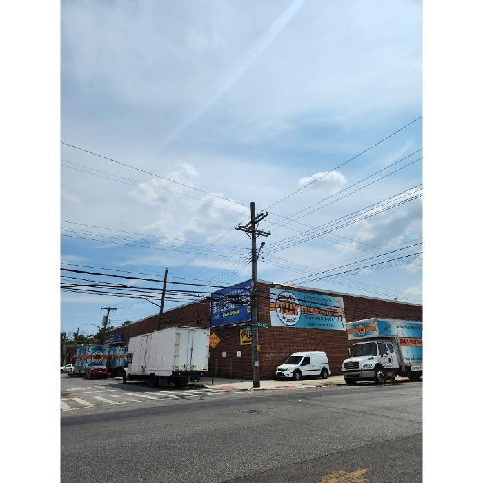 The exterior of the TDY Moving & Storage headquarters and storage warehouse facility in Brooklyn, NY, featuring large blue company signage and parked moving trucks.