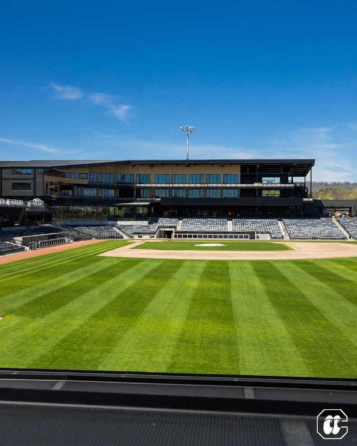 Wide view from the outfield at Erlanger Park, highlighting the Chattanooga Lookouts&rsquo; field, striped grass, and grandstand under a clear blue sky.