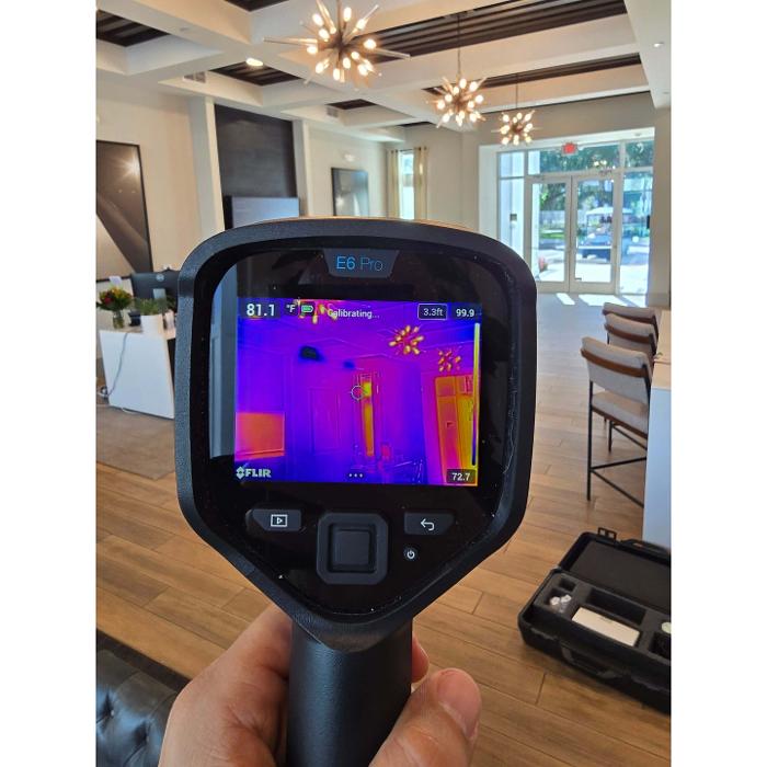 A thermal imaging camera is being used inside a home to identify temperature differences that may indicate moisture intrusion or air quality issues.
