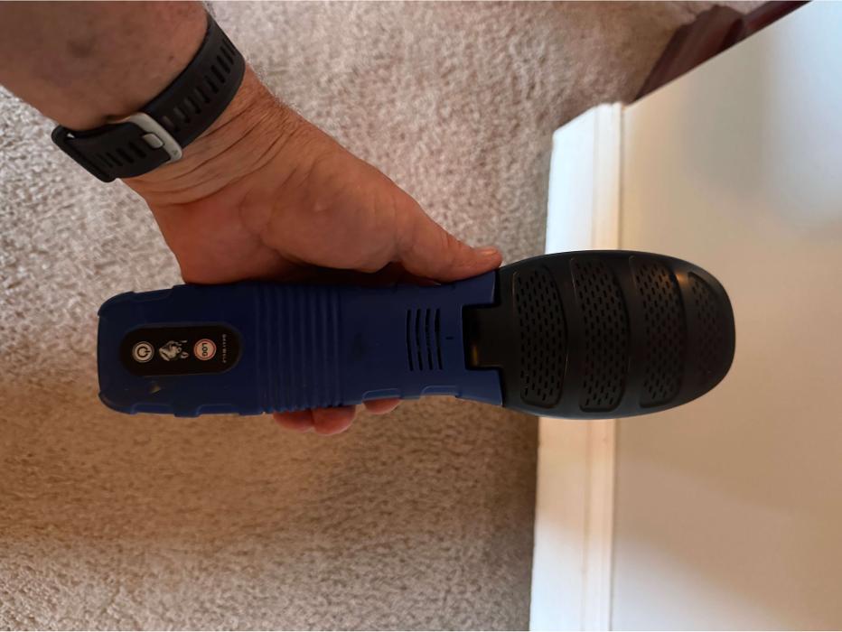 A handheld inspection device is being used on the carpet to check for moisture or other environmental conditions inside the home.