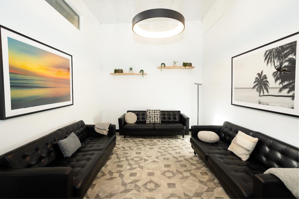 A comfortable lounge area featuring a large, plush black sectional sofa and modern lighting, designed to offer a relaxing and safe environment for group discussions or downtime.