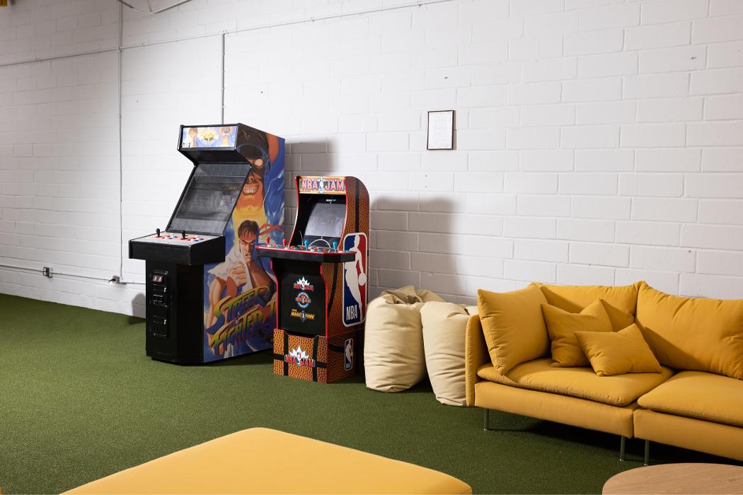 A welcoming and comfortable teen lounge at Key Healthcare Adolescent Outpatient, featuring a bright yellow sofa, green flooring, and an arcade machine to provide a relaxing and engaging environment for youth.
