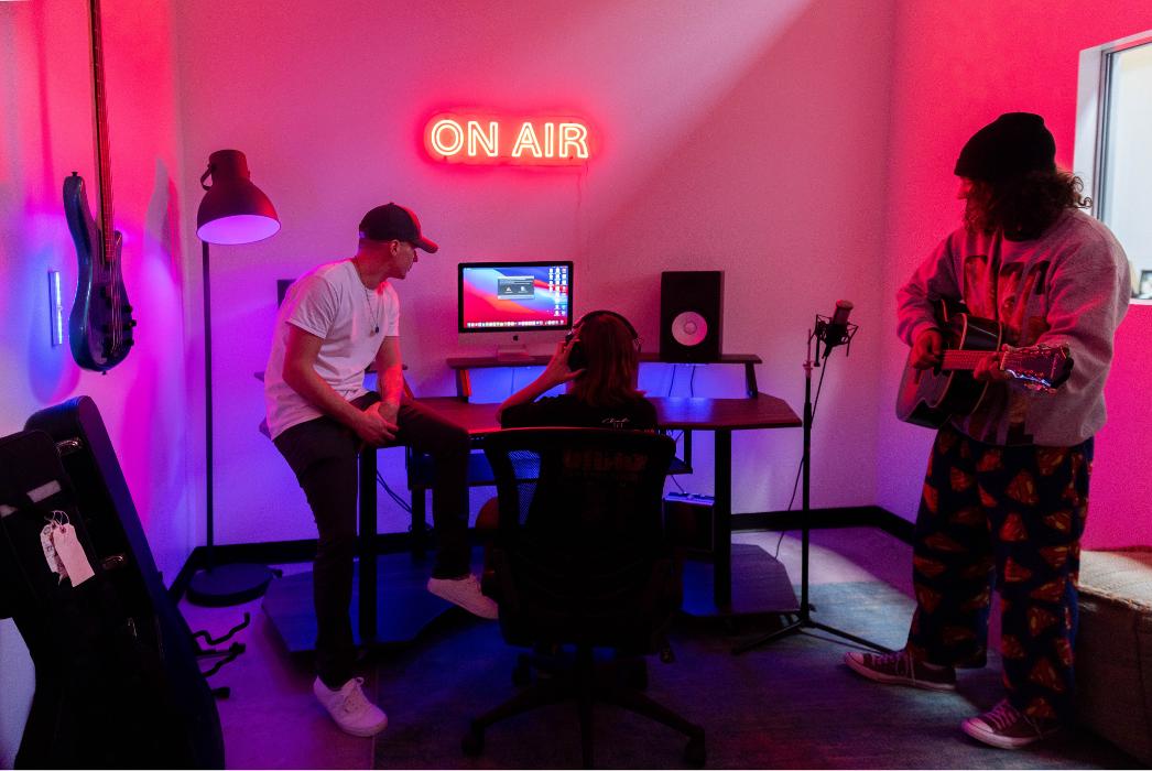 A vibrant creative studio space featuring an "ON AIR" neon sign, designed to encourage self-expression, media engagement, and creative coping skills for our teens.