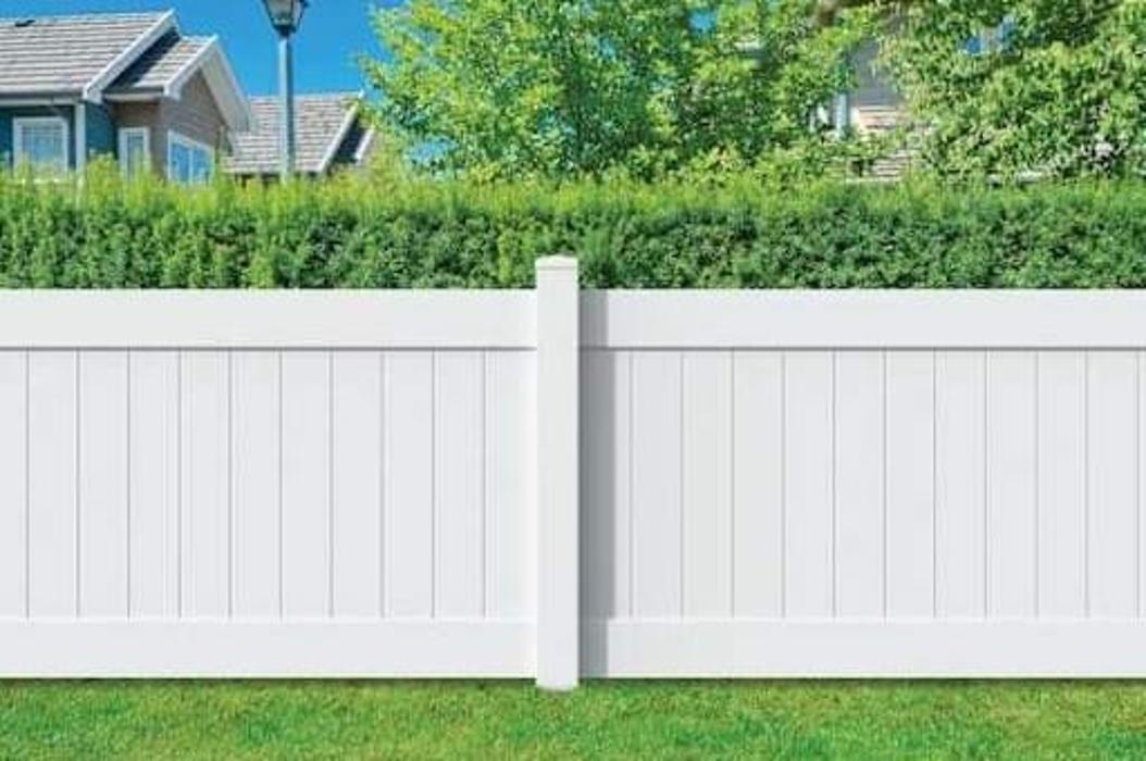 Solid white vinyl privacy fence along a green backyard.