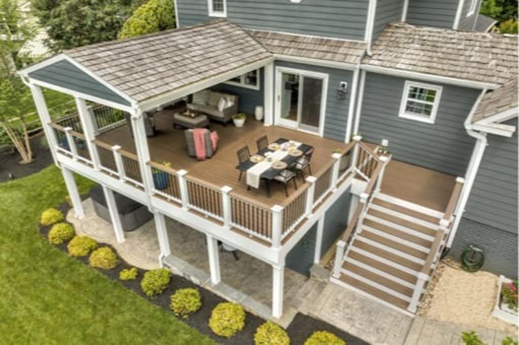 Elevated covered deck with dining area, stairs, and finished patio below.