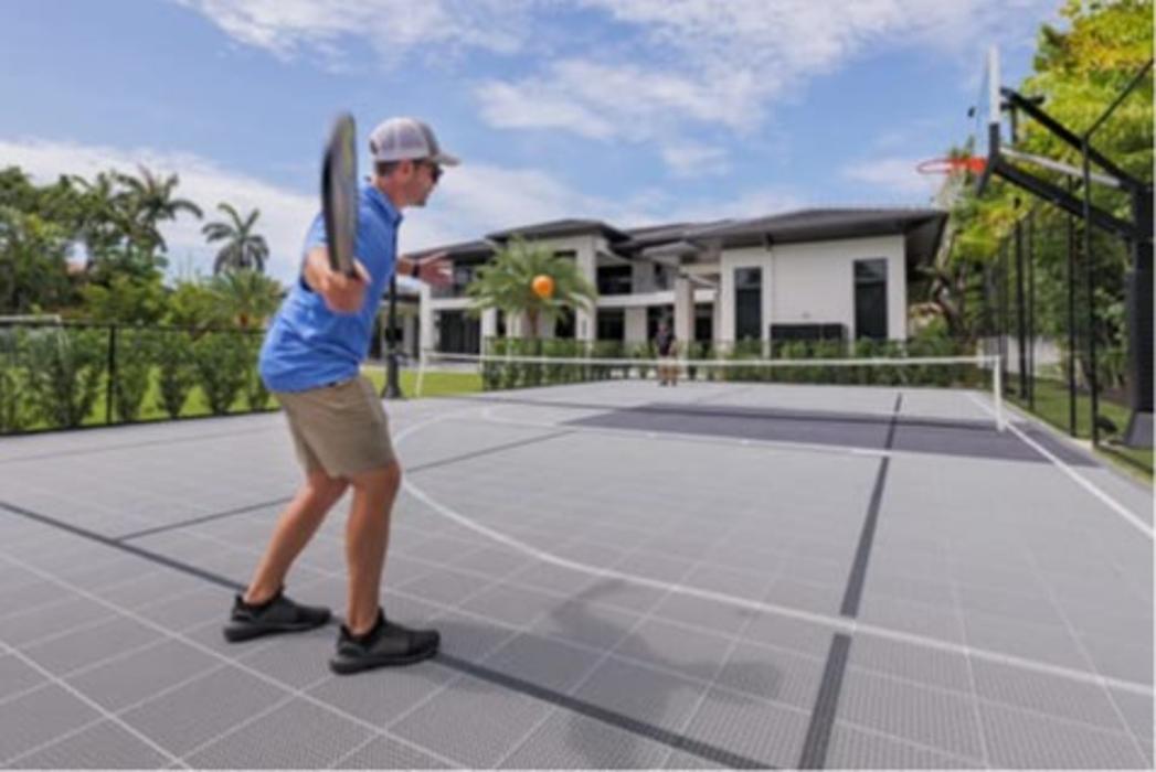 Backyard multi-sport court with pickleball and basketball in front of a modern home.