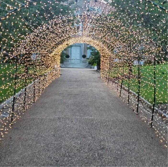 A stunning lighted tunnel display covered in sparkling string lights, creating a magical walkway for guests and visitors.

