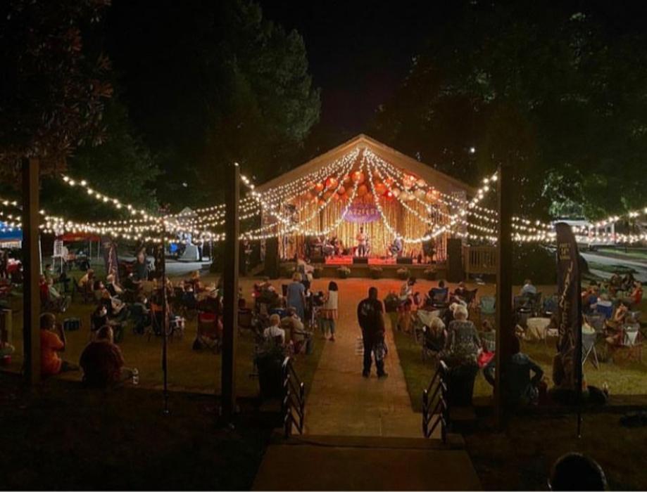 A festive outdoor venue featuring overhead string lights and illuminated d&eacute;cor, creating a warm and inviting setting for guests.