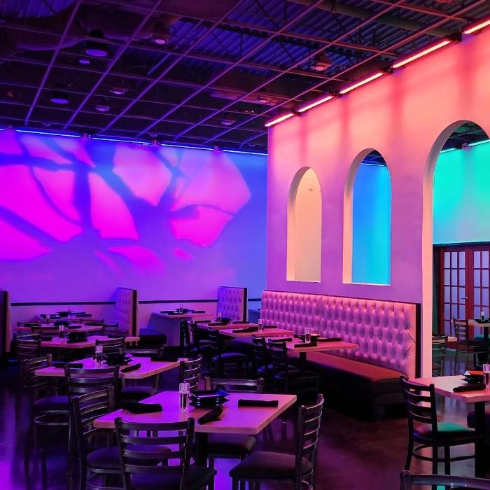 A stylish indoor event space featuring colorful custom lighting that highlights the walls and architecture for a modern, upscale look.