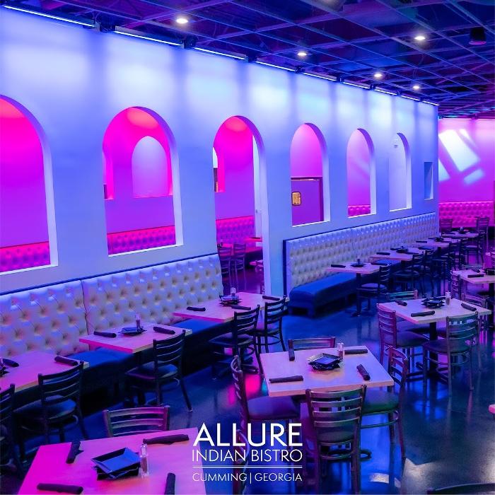 A spacious event venue illuminated with vibrant pink and purple uplighting, creating a bold and elegant atmosphere for a private celebration.