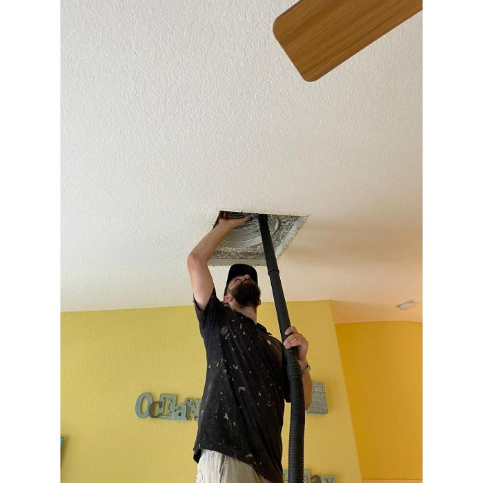 Clean Air Pros technician removing dust and buildup from a ceiling vent to help improve airflow and indoor air quality.