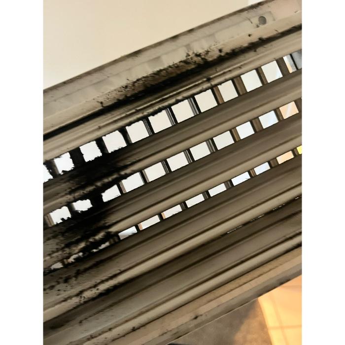 Close-up of metal vent or duct components showing collected dust and buildup, emphasizing the need for HVAC and duct cleaning maintenance.