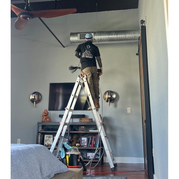 Clean Air Pros technician using specialized equipment to clean or inspect a ceiling vent during residential HVAC maintenance.