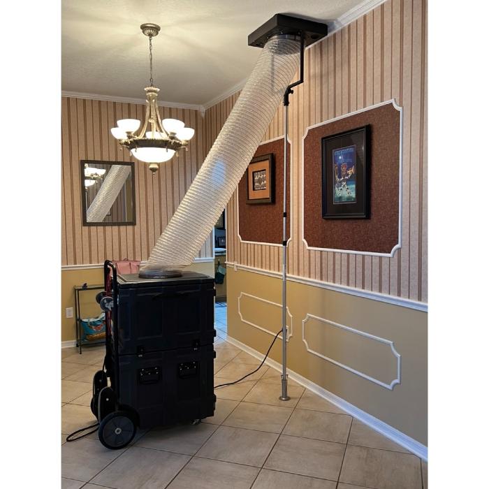 Professional negative air machine and vacuum hose attached to an interior vent as part of a residential air duct cleaning service.
