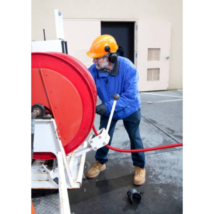 Technician operating high-pressure hydro jetting equipment for commercial drain cleaning