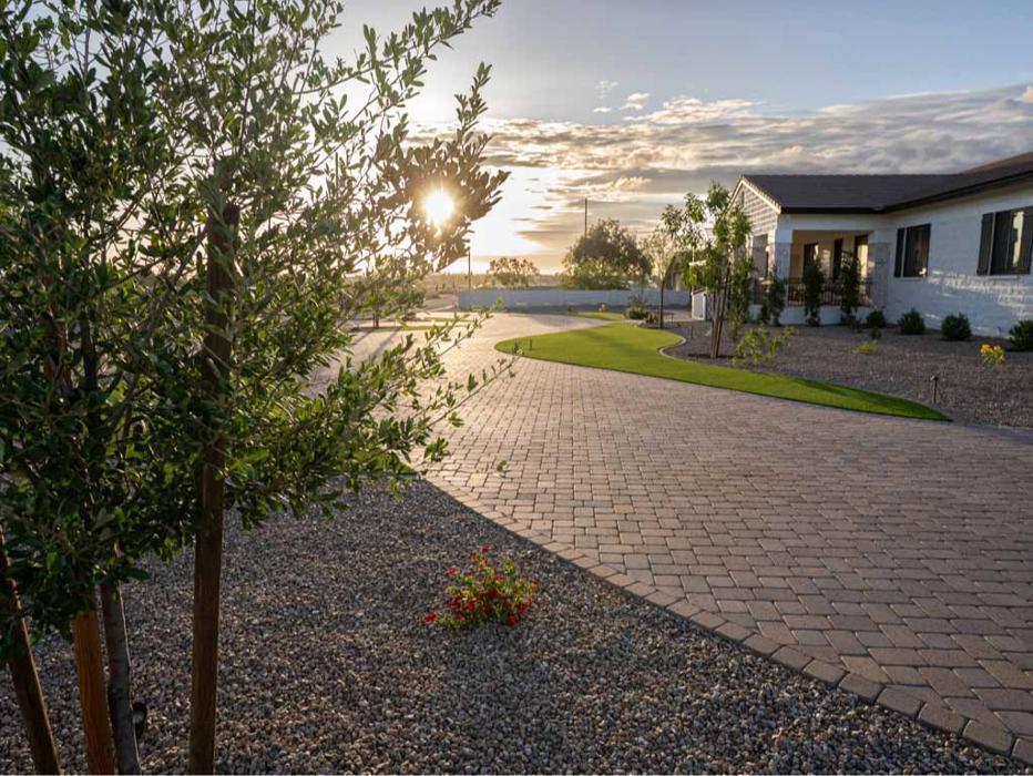 Newly installed paver driveway leading to a modern Arizona residence, captured at golden hour with native desert plantings.
