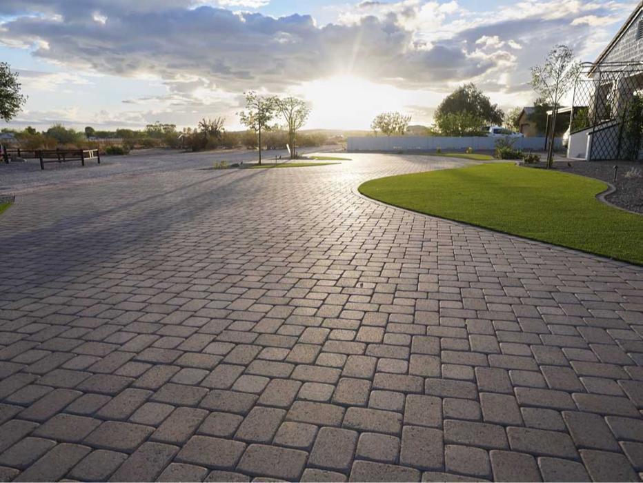 Custom paver driveway installation with hand laid running bond pattern leading to a modern Arizona home.