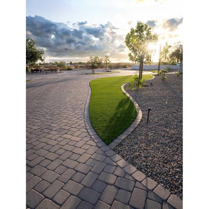 Curved paver pathway wrapping a custom artificial turf lawn with decorative gravel borders and a mature shade tree.