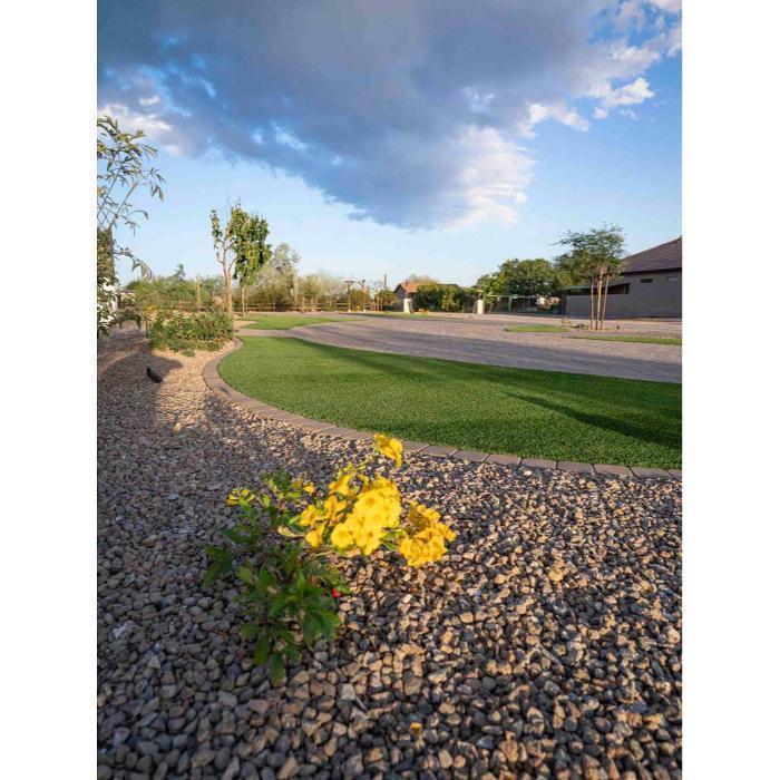 Low water desert landscape featuring decorative rock, a drought tolerant yellow lantana, and an artificial turf accent for year round curb appeal.