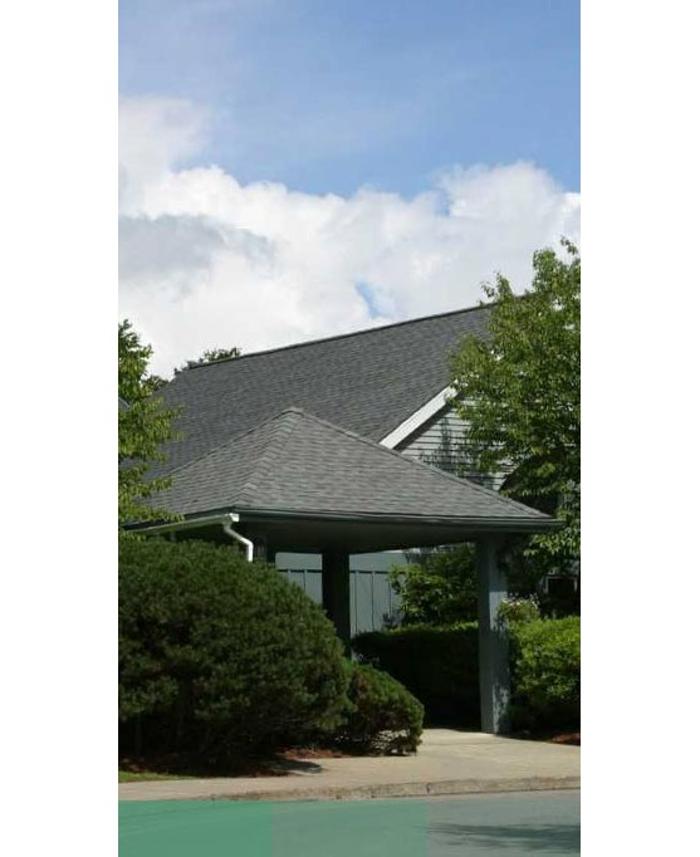 Exterior view of Arms Acres, an inpatient addiction treatment and drug and alcohol detox center in Carmel Hamlet, New York, with a covered entrance, landscaped shrubs, and trees.