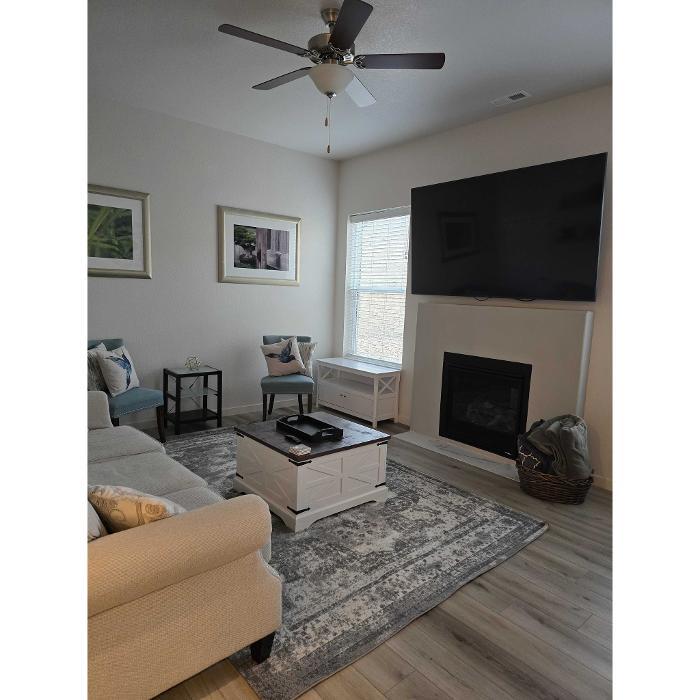 Clean living room with sofa, rug, fireplace, wall-mounted TV, and bright window in a Colorado Springs home.