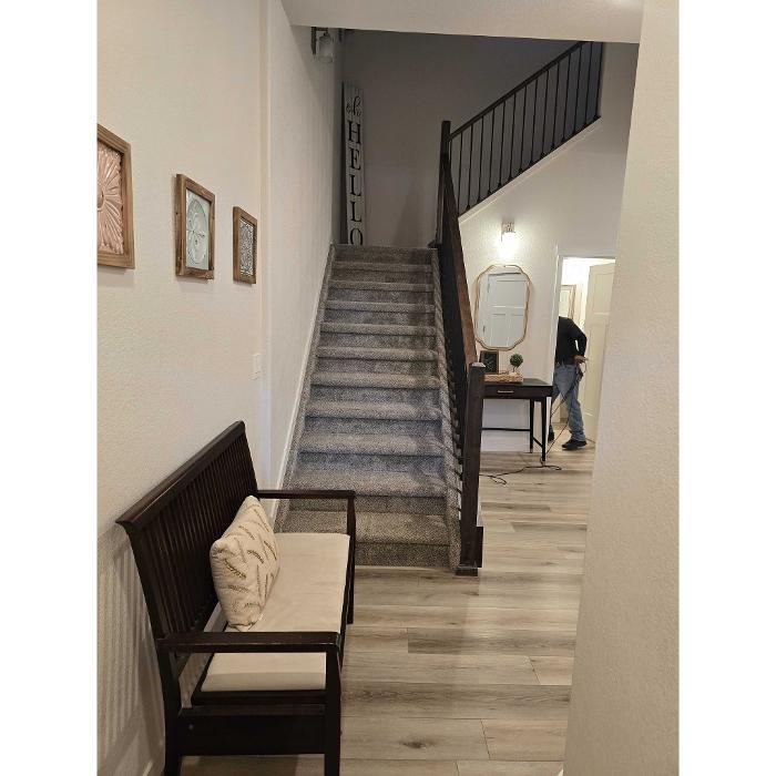 Clean entryway with bench, wood flooring, carpeted stairs, and home decor in a Colorado Springs home.
