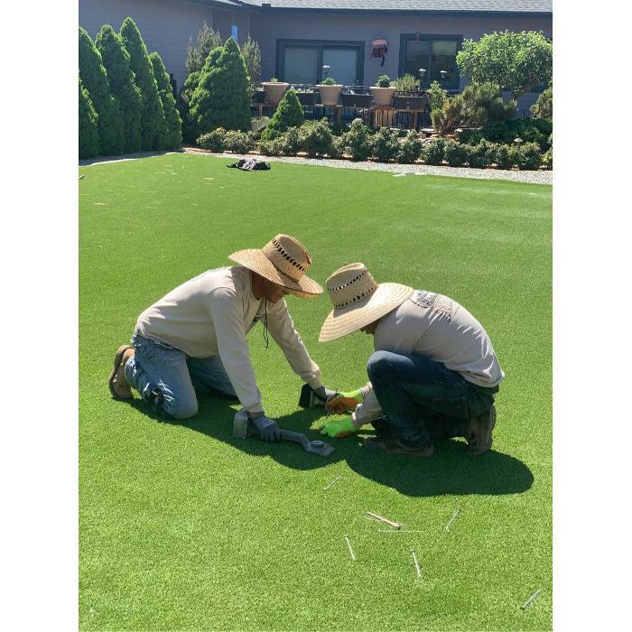 Ayala's Landscape Professionals crew member installing artificial turf or sod in a residential yard in Prescott Valley, AZ