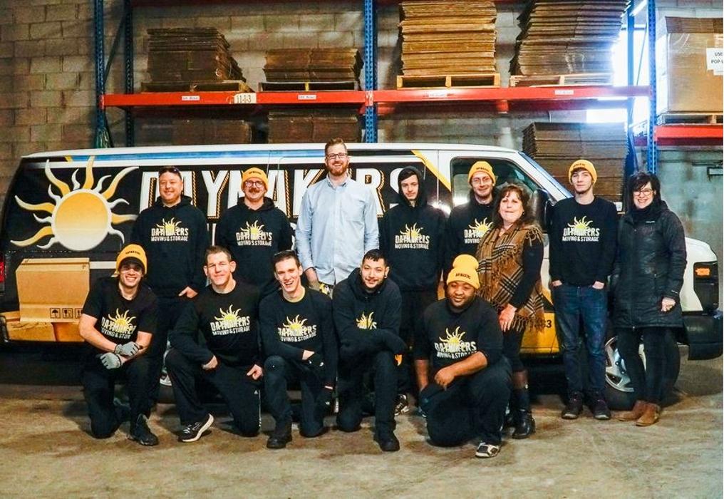 Daymakers Moving & Storage team posing in warehouse in Bloomington, MN in front of branded moving truck and stacked boxes