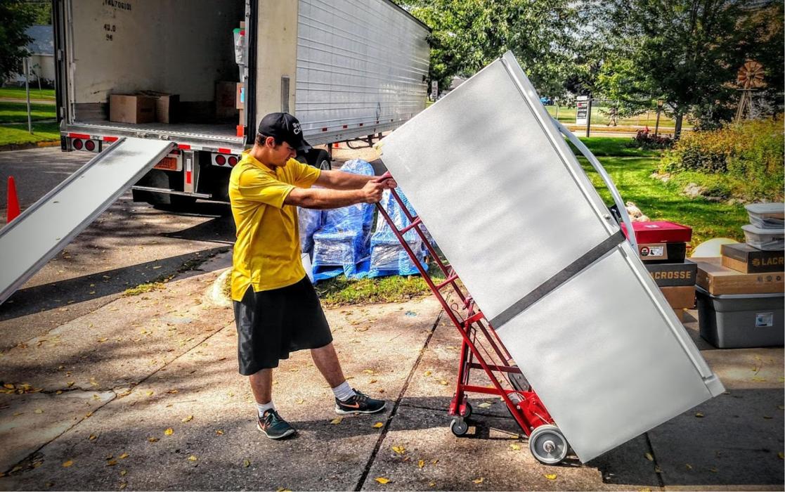 Daymakers Moving & Storage mover loads an appliance onto a dolly beside a moving truck in Roseville, MN.