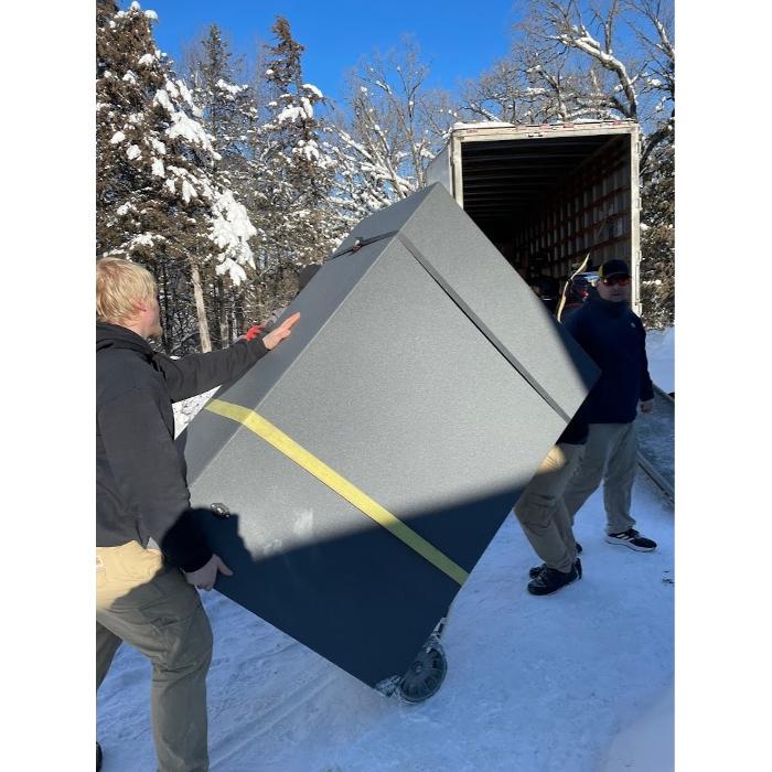 Daymakers Moving & Storage movers unload a large gray cabinet from a truck in snowy Roseville, MN.