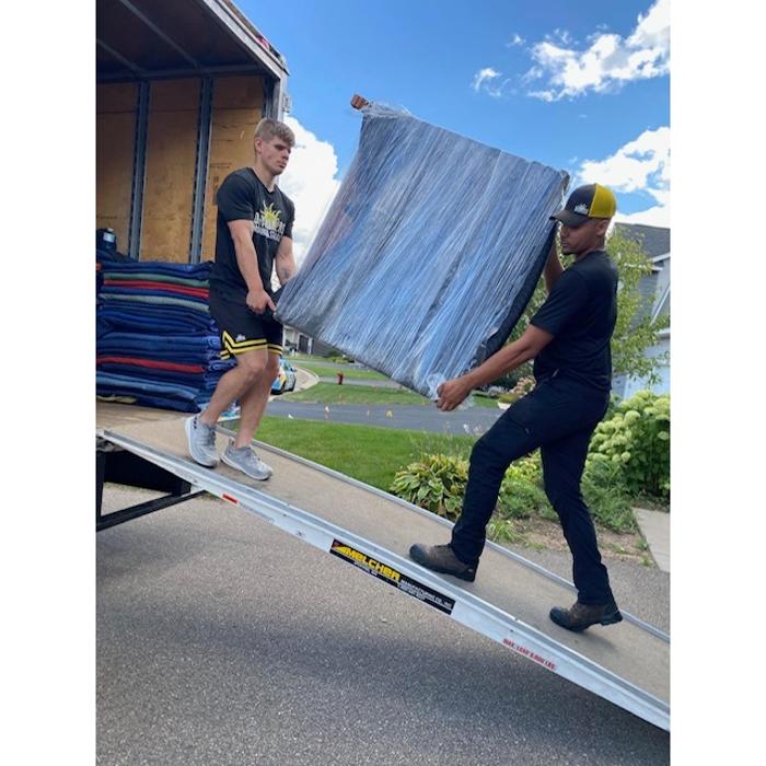 Daymakers Moving & Storage movers load a wrapped item onto a truck ramp in Lake Elmo, Minnesota.