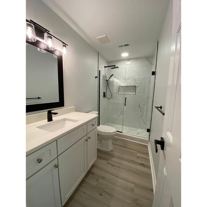 Bathroom renovation featuring a glass shower, updated vanity, modern fixtures, fresh flooring, and clean finish work.