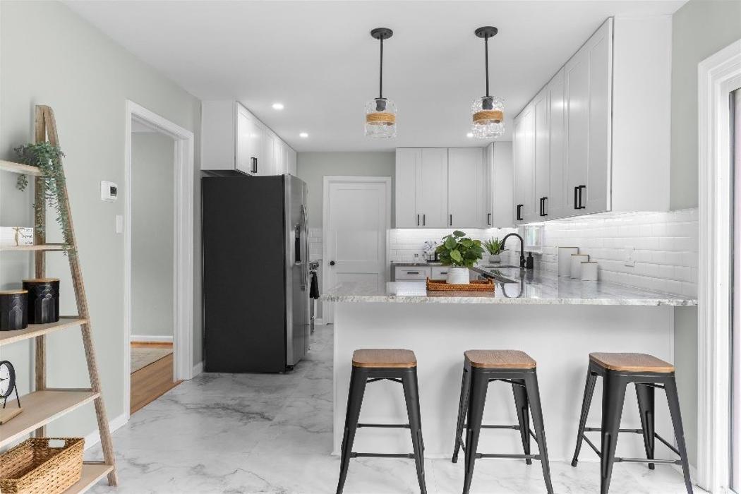 Bright kitchen remodeling project featuring white cabinetry, island seating, pendant lighting, updated flooring, and modern finishes.