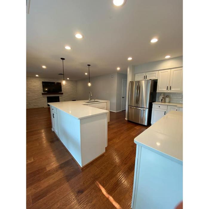 Kitchen remodeling project featuring a large island, white cabinetry, recessed lighting, stainless steel appliances, and updated flooring for a clean, modern layout.
