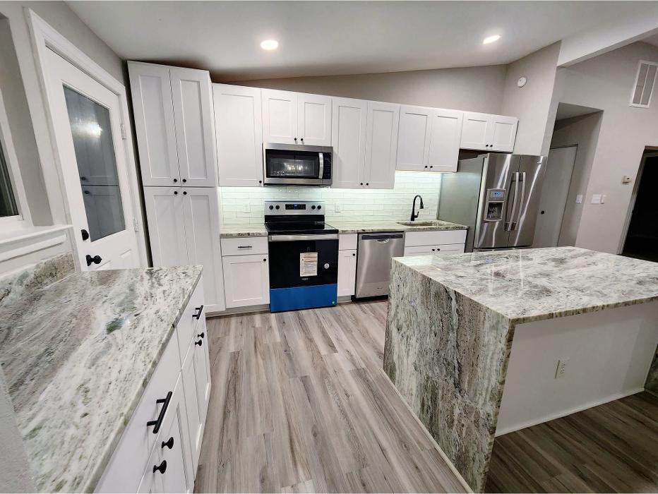 Kitchen renovation with new cabinetry, countertops, flooring, appliances, and a refreshed open layout by Divine Touch Home Improvements.