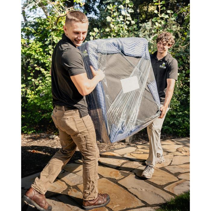 Best of Utah movers carrying a wrapped chair through a Salt Lake City yard